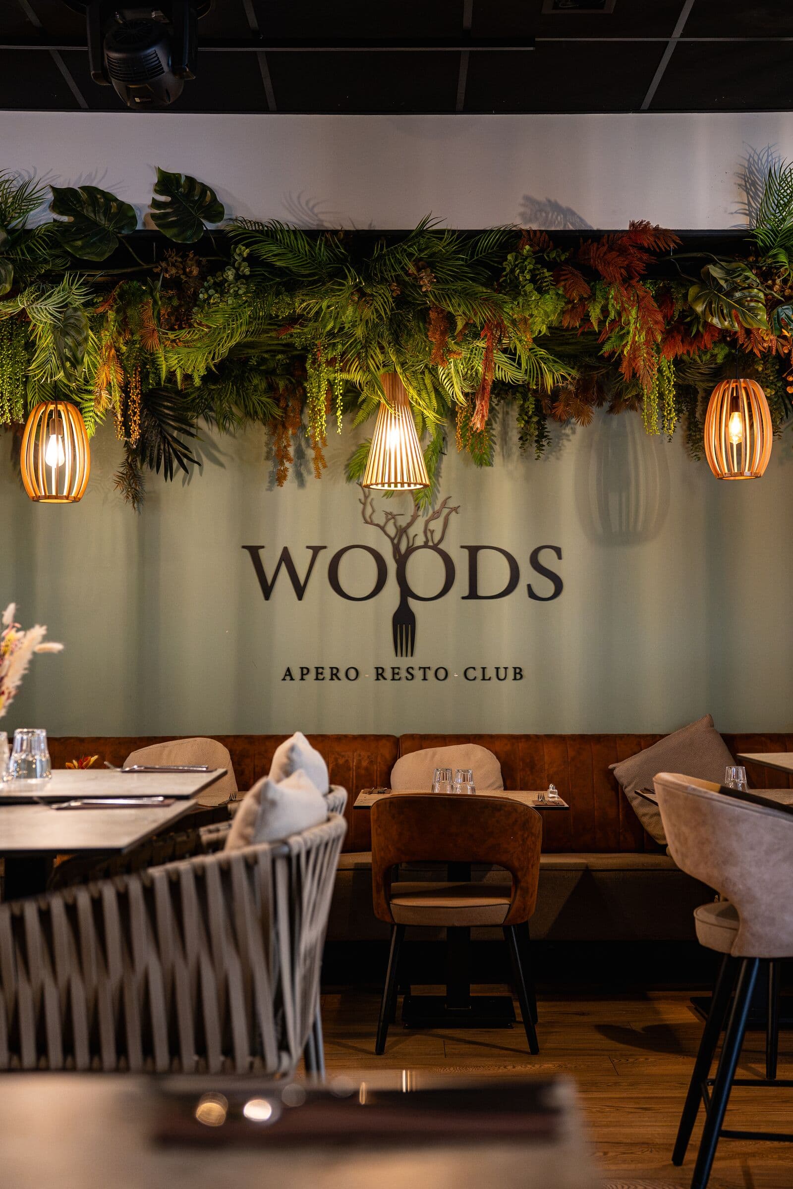 Salle jungle chic du restaurant WOODS à Bourgoin-Jallieu, enseigne sous un mur végétal
