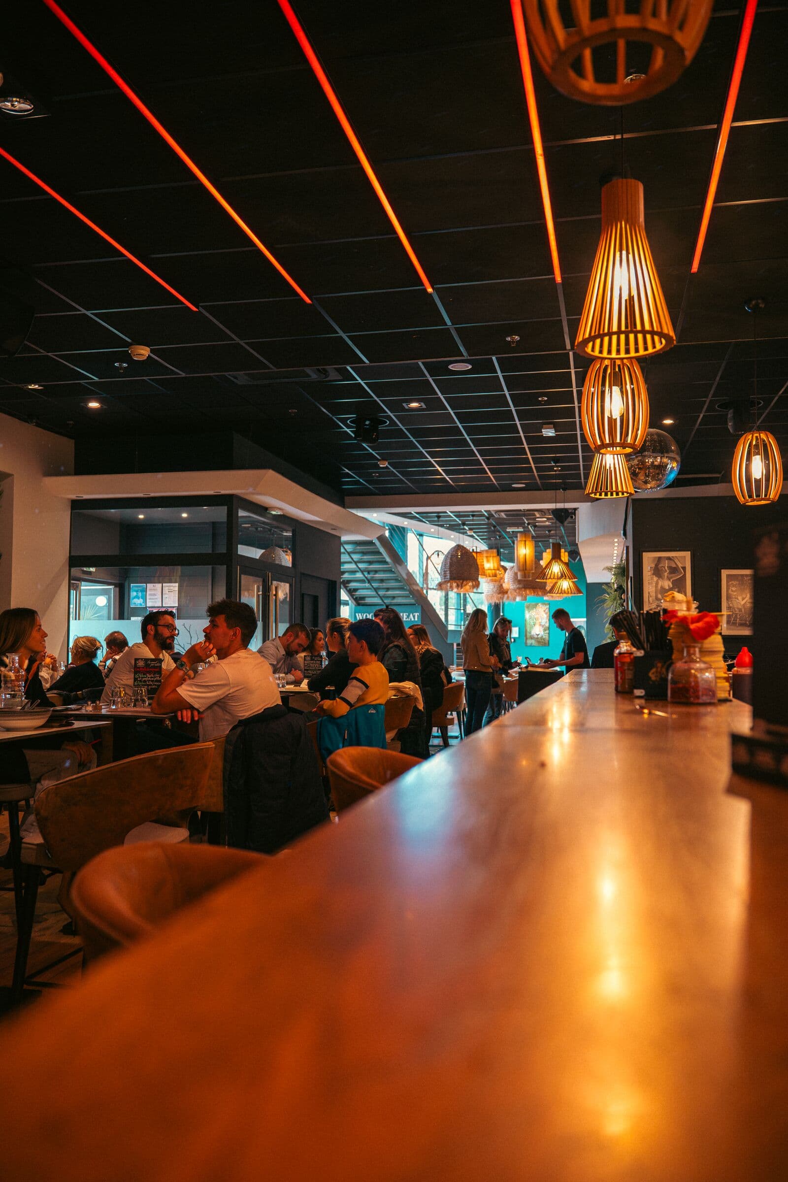Long comptoir en bois et salle pleine un soir au WOODS