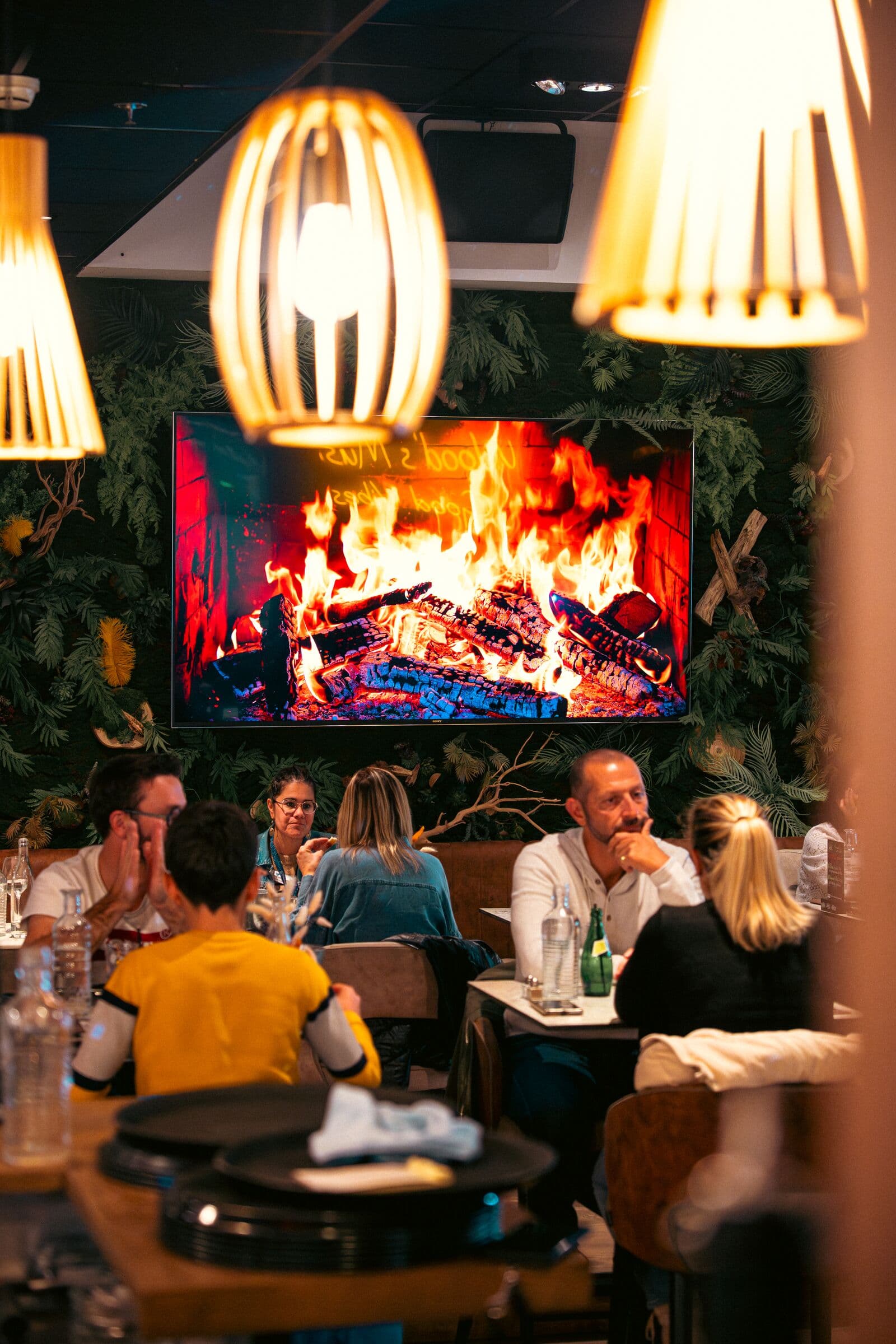 Clients attablés dans l’ambiance feu de bois du restaurant WOODS